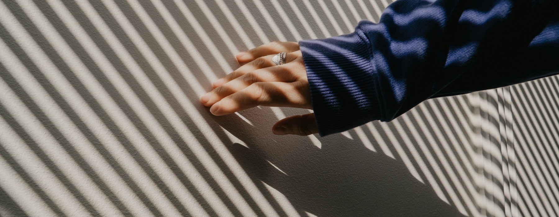 lifestyle image of a person running their hand along a wall